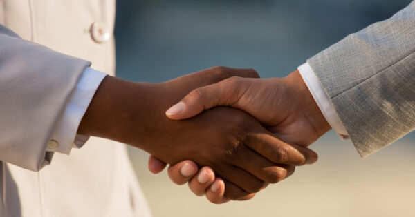 Dark skinned businesswoman shaking hands with male colleague Dark skinned businesswoman shaking hands with male colleague. Closeup of business people handshake. Agreement concept